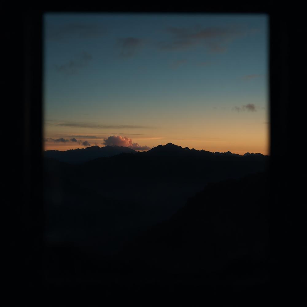 Paisagem de montanhas ao entardecer vista por uma janela
